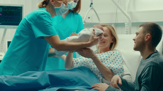 在医院里，妇女在分娩，婴儿出来，产科医生帮助分娩，丈夫支持妻子。侧面镜头。视频素材
