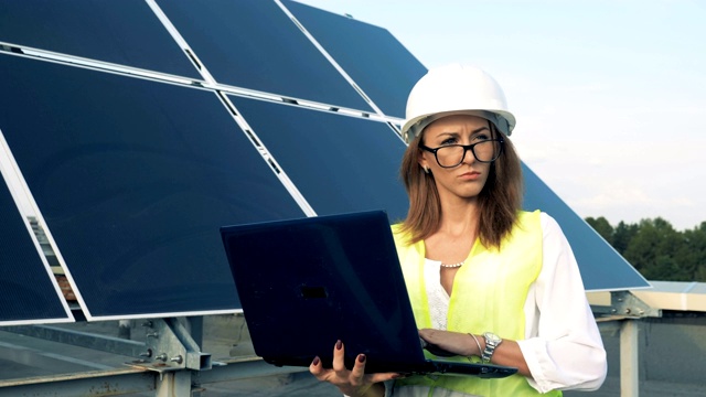 女人一边在笔记本电脑上打字，一边走到太阳能电池旁边。视频下载