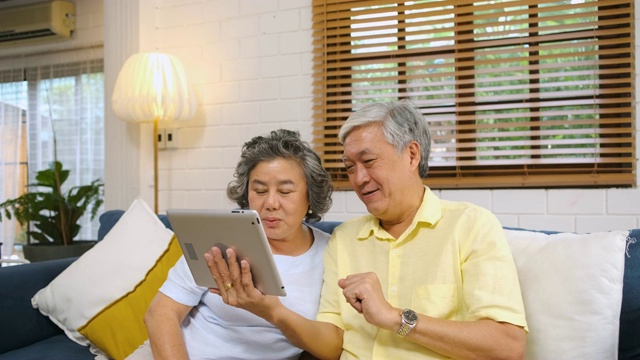 亚洲老年夫妇使用平板电脑facetime和孙子聊天视频素材