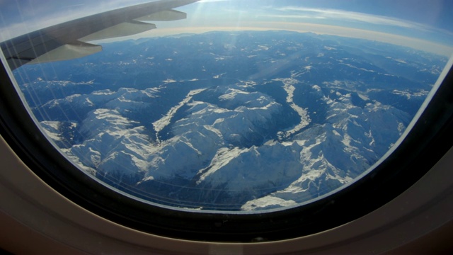 飞机窗口的景色与美丽的白雪覆盖的山脉视频素材
