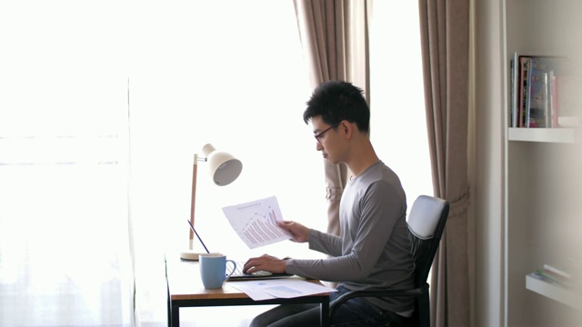 男人在家里的工作空间用笔记本电脑工作，慢镜头视频素材