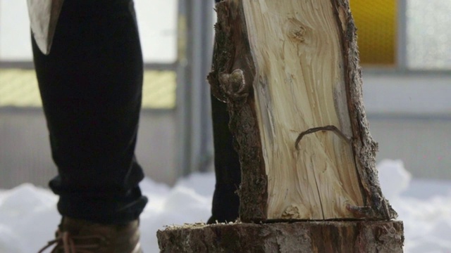 一个人在冬日村庄的雪院里砍柴的慢镜头视频素材