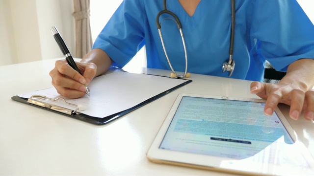 女医生在病历上写字，在平板电脑上分析，慢动作视频素材