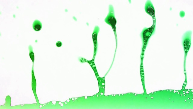 绿色液体与宏观喷溅和喷溅为项目的一个时髦的揭示效果视频素材
