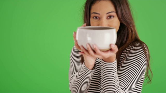 拉丁裔女性举着陶瓷碗，对着绿色屏幕上的镜头微笑视频下载