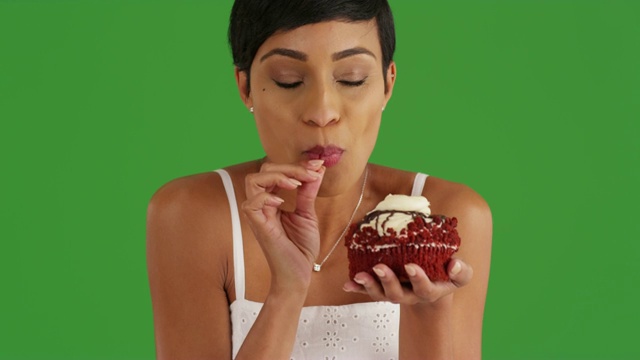 黑色女性享受款待，品尝杯蛋糕上的绿色屏幕视频素材