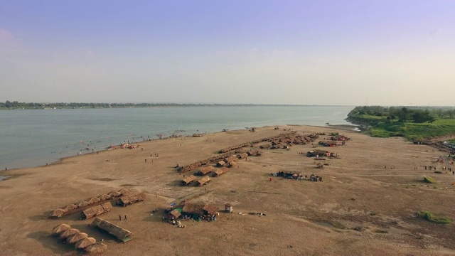 无人机拍摄:飞过散布在沙滩上的稻草小屋和木屋视频素材