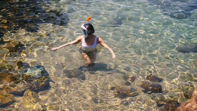 年轻女子浮潜在蓝色的热带水穿着白色泳衣视频素材