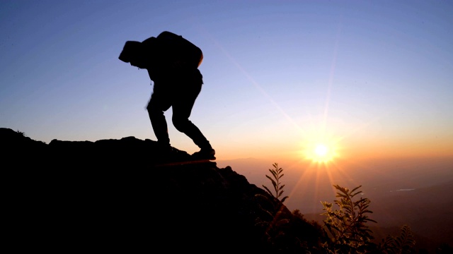 4K WS男人带着太阳耀斑爬上山顶。视频素材