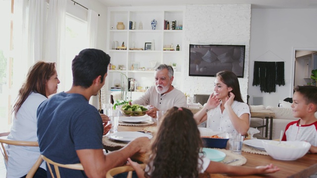 三代拉美裔家庭围坐在餐桌前准备晚餐视频素材