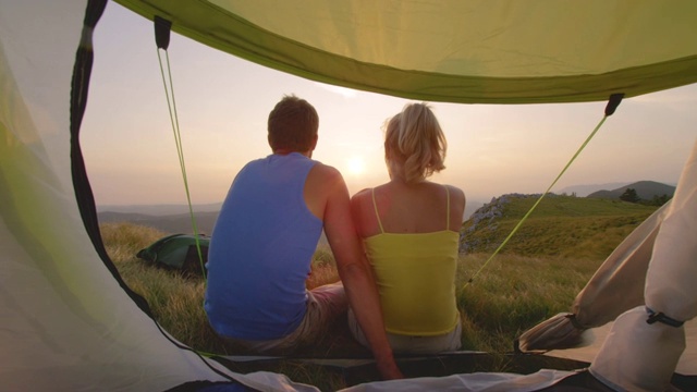 太阳耀斑:清晨金色的阳光照在坐在帐篷前的夫妇身上。视频素材