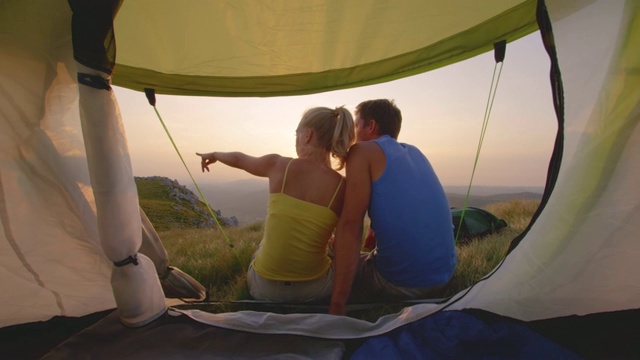 慢镜头:一对活跃的夫妇在阿尔卑斯山露营，观看金色的日落。视频素材