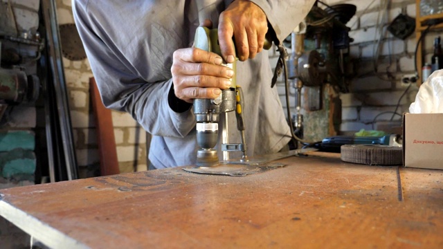 在修理车间操作时，机械师的男性手握着工具。男人在他的车库里工作。成年工人在工作表面处理细节。努力工作的概念。慢动作近距离拍摄视频下载