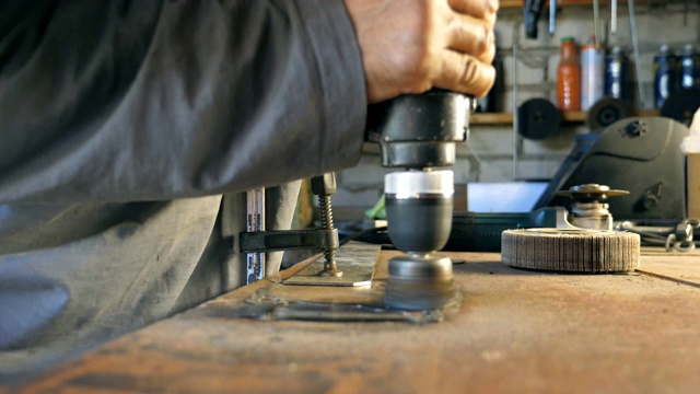 在维修车间操作时，机械师的男性手握住工具。男人在他的车库或车间工作。工人在工作面上处理细节。努力工作的概念。慢镜头视频下载