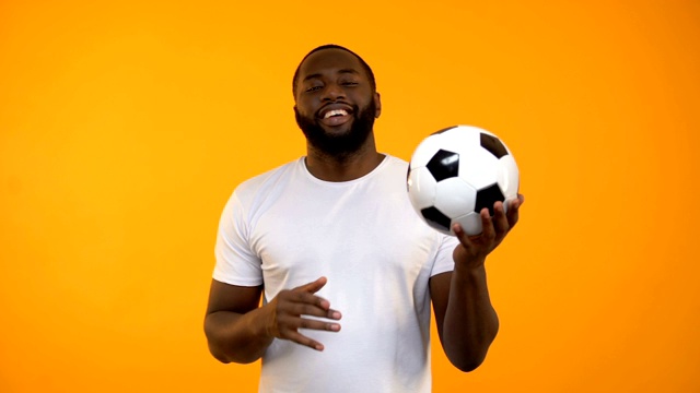 美国黑人男子笑着踢足球，健康的生活方式，运动视频素材