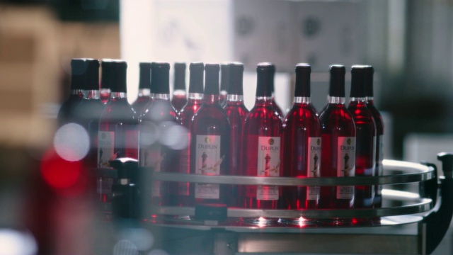 SLOMO。酒厂员工从旋转的展示台上拿起两瓶红酒。视频素材