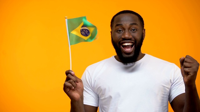 快乐的黑人举着巴西国旗，球迷支持国家足球队视频素材
