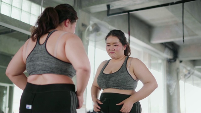 在健身房里照镜子的胖女人。视频素材