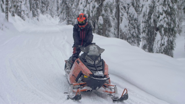 一个男人在山里驾驶雪上摩托时启动了他的雪上摩托。——慢动作视频下载