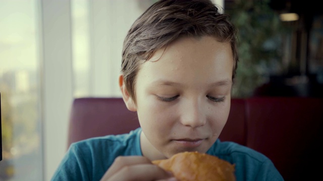 镜头快乐的青少年吃美味的汉堡在快餐店。视频素材