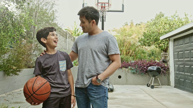 父亲与儿子在院子里拿着篮球交谈的实时视频视频素材