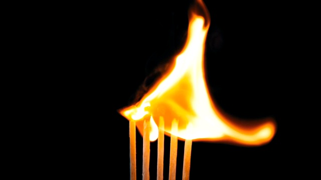五根点燃的火柴和火焰在黑色背景上的连锁反应视频素材