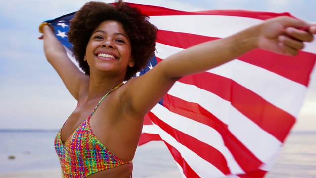 快乐的非洲女人在海滩上举着美国国旗视频下载