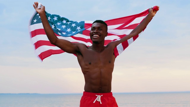 快乐的非洲人在海滩上举着美国国旗视频下载