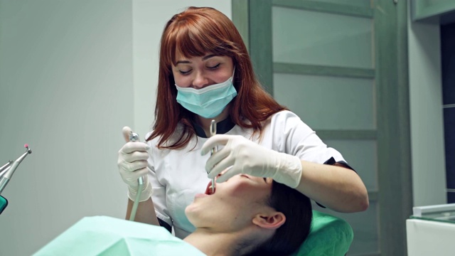 年轻女性病人张大嘴巴，在牙科诊所进行牙科检查。视频素材