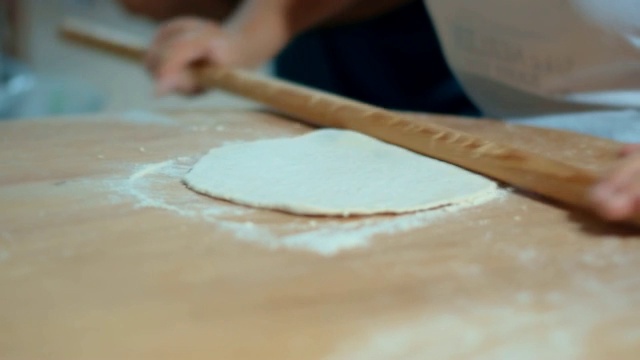 人的双手用擀面杖擀出一片面团。烹饪烘焙产品视频素材