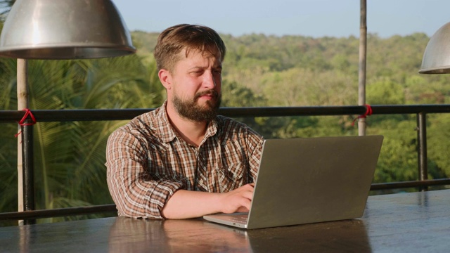 长着胡子的帅哥在户外用笔记本电脑打字视频素材