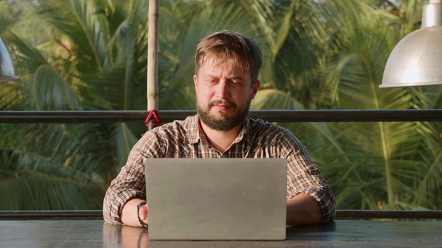 英俊的胡子男子打开笔记本电脑，开始户外工作视频素材