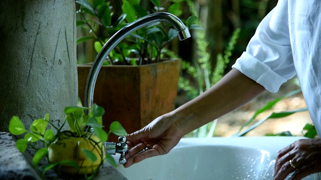 一个女人在室外花园的水槽里洗手。视频素材