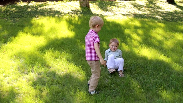 两个快乐的小男孩在公园的草地上玩得很开心。视频素材