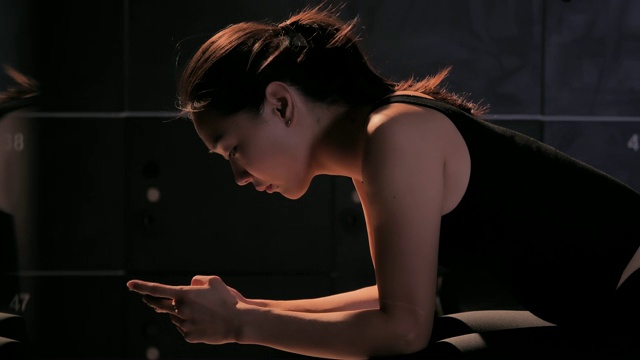 年轻女子在智能手机上发信息，锻炼的时候休息。运动准备视频素材