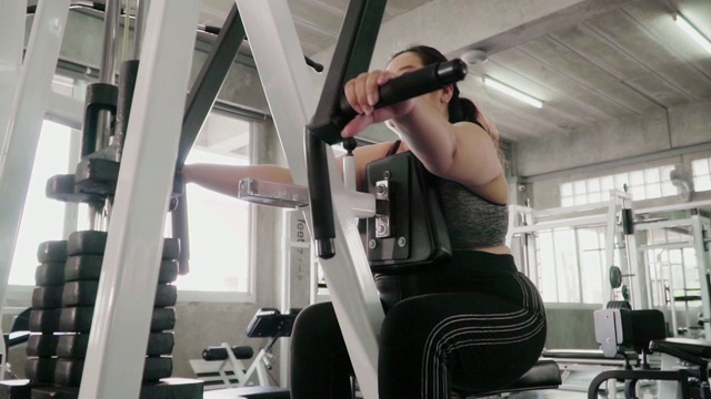 (慢镜头)超重妇女在健身房里使用运动器械减肥。视频素材