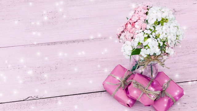 粉红色的木制背景上，鲜花和礼物闪烁视频素材
