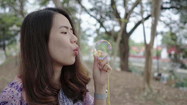 美丽的亚洲女人吹大泡泡在花园里视频素材