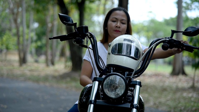 女性在她的摩托车上戴着头盔。视频下载