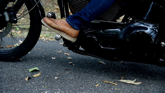 脚踏女人在摩托车上的靴子的特写。视频素材