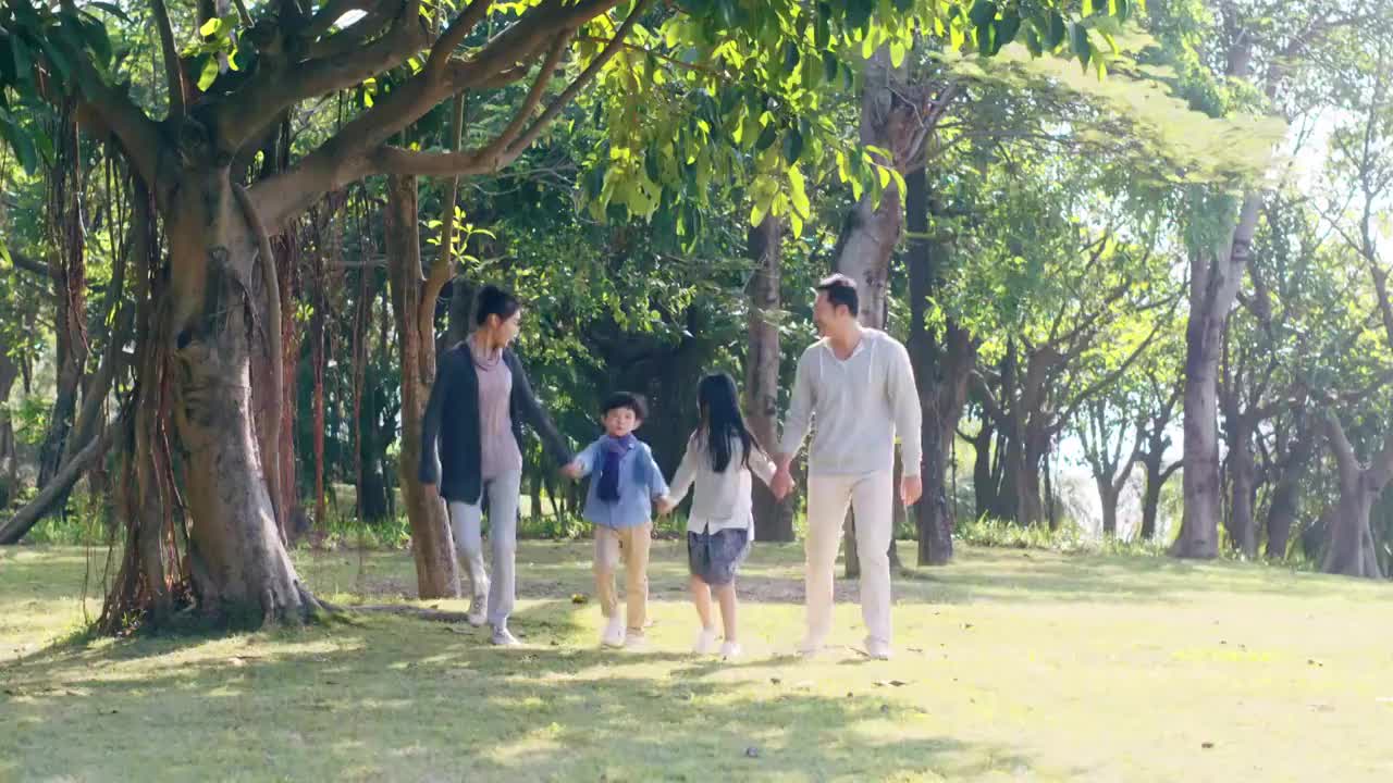 一个亚洲家庭带着两个孩子在公园散步视频素材