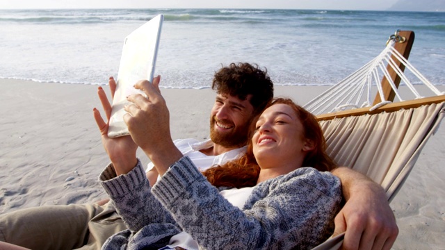 夫妇在沙滩上使用数码平板电脑4k视频素材