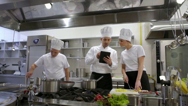 忙碌的厨师和厨房厨师咨询平板电脑视频素材