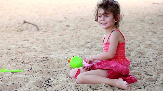 快乐的小女孩在沙滩上玩沙子视频素材