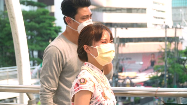 以下侧视图:年轻的中国女子和男友戴着面具在雾霾的城市里视频素材