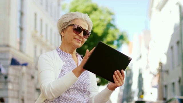 在城市街道上拿着平板电脑的老妇人视频素材