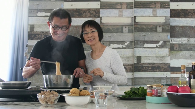 一名中国男子和一名中国女子在微笑着准备饭菜视频素材