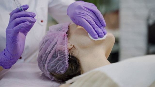 美容师双手戴手套，在女性颈部进行脸部抗衰老注射。视频素材