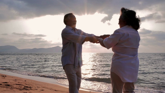 一对高年级情侣在阳光明媚的日子里在沙滩上跳舞，一对高年级情侣在海边放松。高级假期,假期视频素材