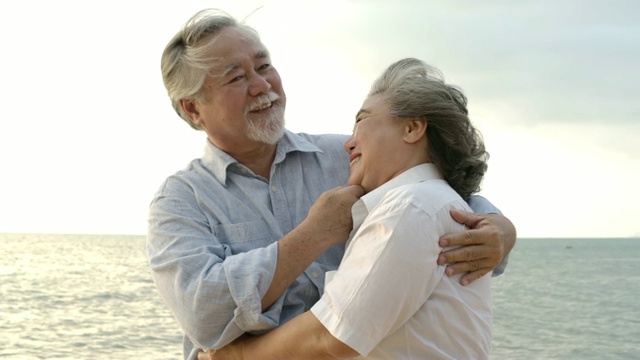 亚洲老年夫妇在海滩上拥抱对方的慢镜头。视频下载